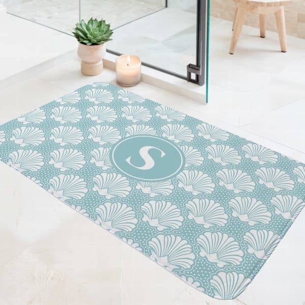 Teal Bath Mat With A White Seashell Pattern And A Central Teal Circle Containing The Letter S.