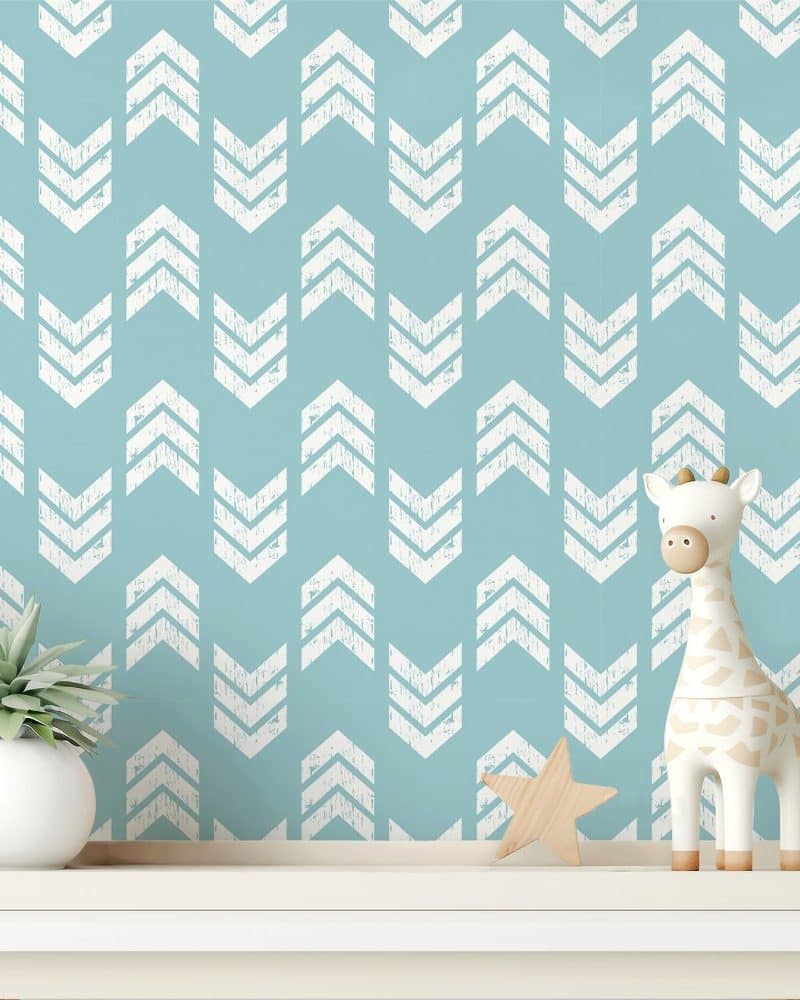 A teal wall with a repeating pattern of white chevron arrows, decorated with a small giraffe toy and a potted plant on a shelf.