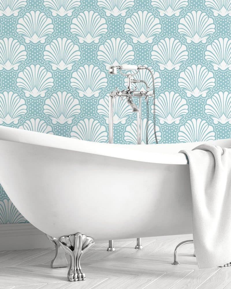 White clawfoot bathtub in front of a teal seashell patterned wall.