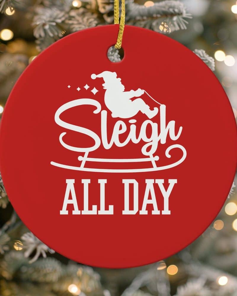 Red round Christmas ornament with a white silhouette of Santa in a sleigh and the text Sleigh All Day.