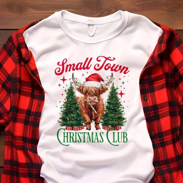White Sweatshirt With A Highland Cow Wearing A Santa Hat, Between Two Christmas Trees, And The Text Small Town Christmas Club.
