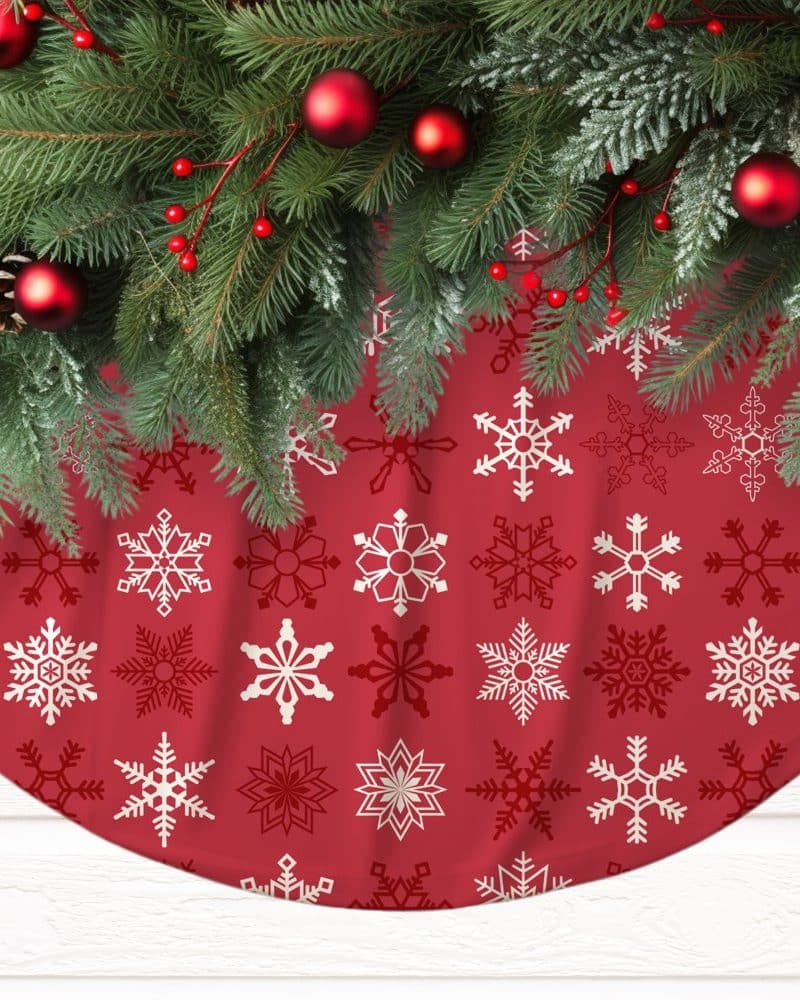 Red Christmas tree skirt with a snowflake pattern, adorned with a fir garland.