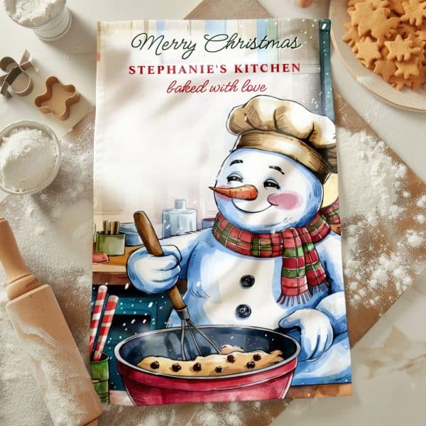 Christmas Tea Towel Featuring A Snowman Chef Baking In A Kitchen.