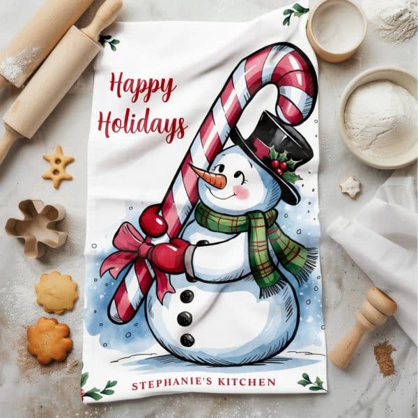 Kitchen Towel With A Happy Holidays Message And Illustration Of A Snowman Holding A Candy Cane.