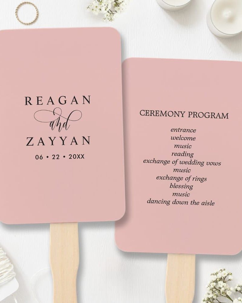 Two blush pink wedding ceremony programs shaped like hand fans; one lists the couple's names and wedding date, the other details the ceremony events.