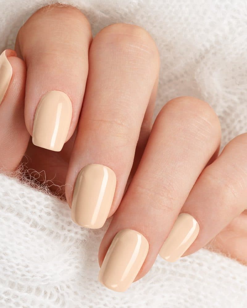 Close-up of a hand with light beige nail polish.