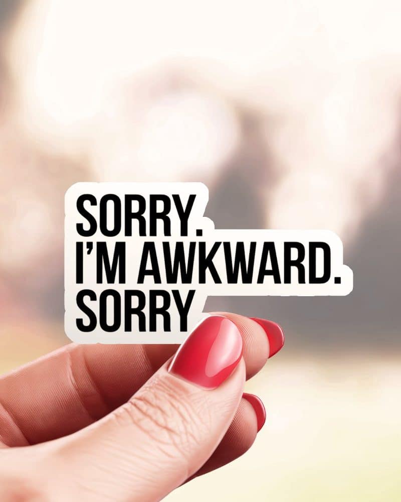 A hand holds a sticker that reads Sorry. I'm awkward. Sorry.