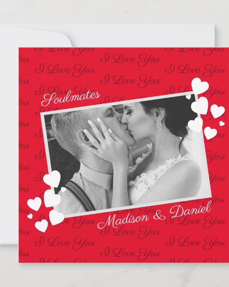 A red card with a black and white photo of a couple kissing. The card features the words "Soulmates" and "Madison & Daniel" along with a repeating "I love you" pattern. White hearts surround the photo.