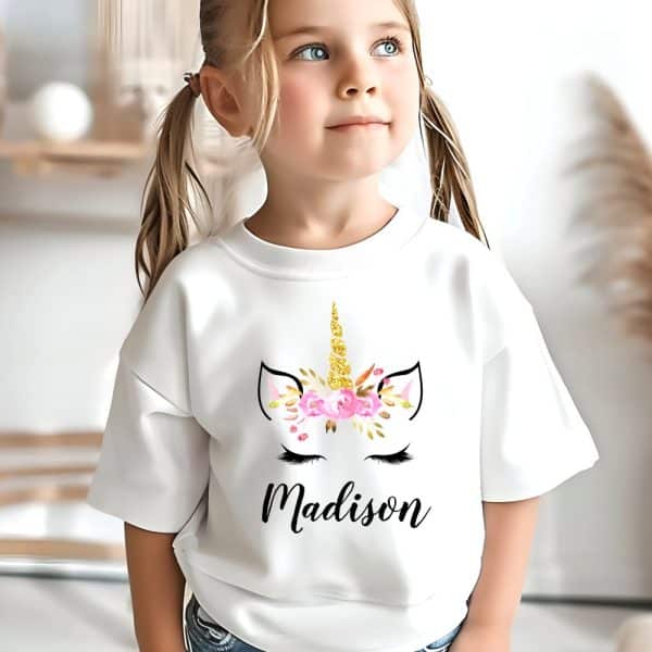 Girl Wearing A White Sweatshirt With A Floral Unicorn Design And Her Name, Madison.