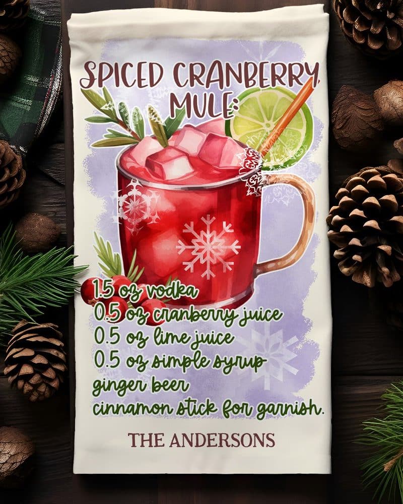 A watercolor illustration of a spiced cranberry mule cocktail recipe on a kitchen towel.