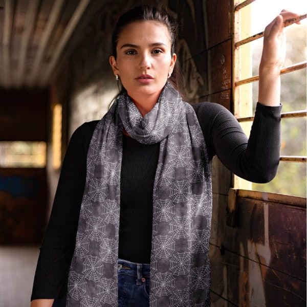 Woman Wearing A Dark Gray Scarf With A White Spiderweb Pattern.