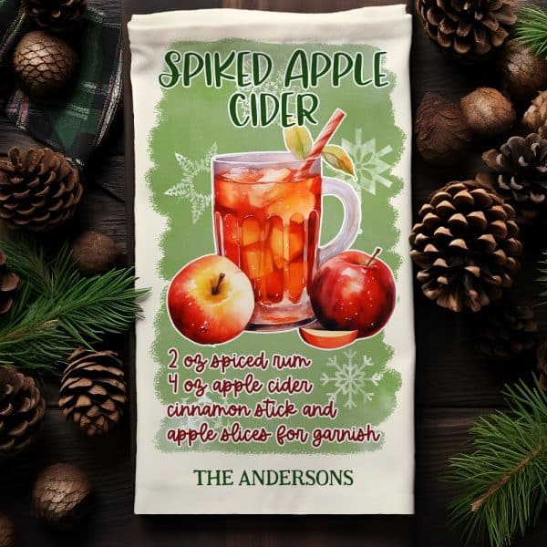 A Kitchen Towel Featuring A Watercolor Illustration Of A Mug Of Spiked Apple Cider With Apples And A Recipe.