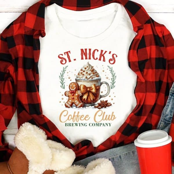 White Shirt With St. Nick'S Coffee Club Brewing Company Logo Featuring A Gingerbread Man And A Coffee Drink.