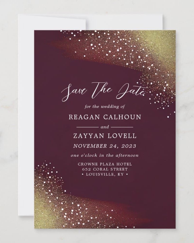 Burgundy save the date card with gold glitter detailing, announcing the wedding of Reagan Calhoun and Zayyan Lovell on November 24, 2023.