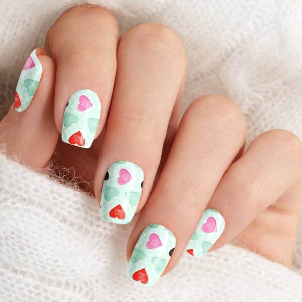 Close-Up Of A Hand With Fingernails Decorated With A Pattern Of Mint Green And Pink Hearts That Say Stay Single.