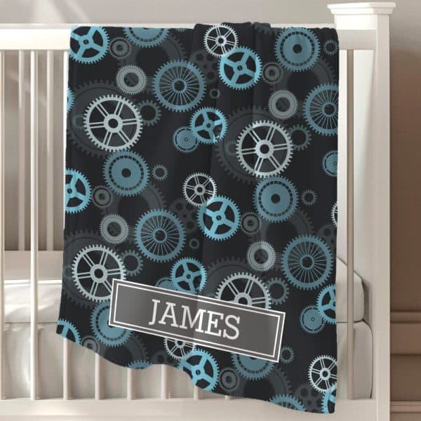 Black Baby Blanket With A Teal And Gray Gear Pattern And The Name James.