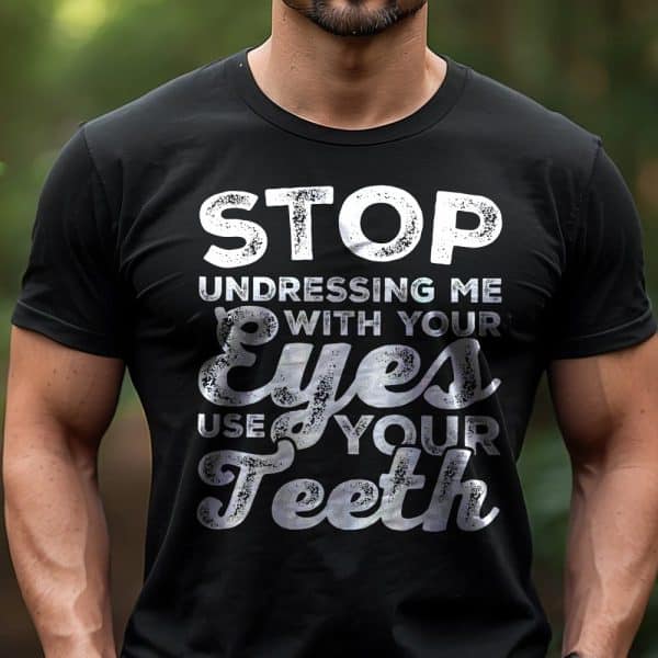Man Wearing A Black T-Shirt With A Humorous Phrase In Distressed White Lettering: Stop Undressing Me With Your Eyes, Use Your Teeth.