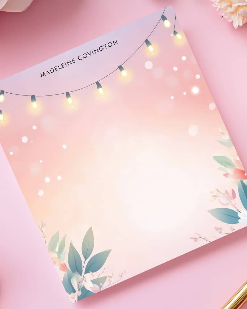 Personalized notepad with pink floral design, string lights, and the name Madeleine Covington.