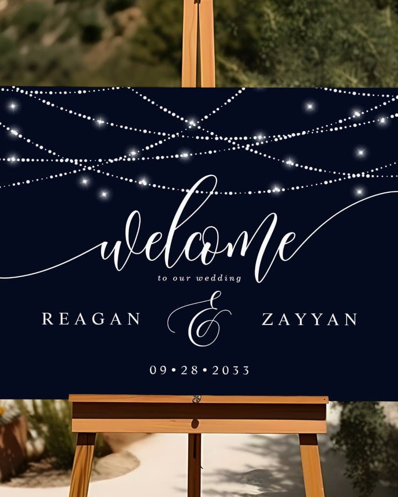 A dark blue wedding welcome sign with string lights, the names Reagan and Zayyan, and the date September 28, 2033.