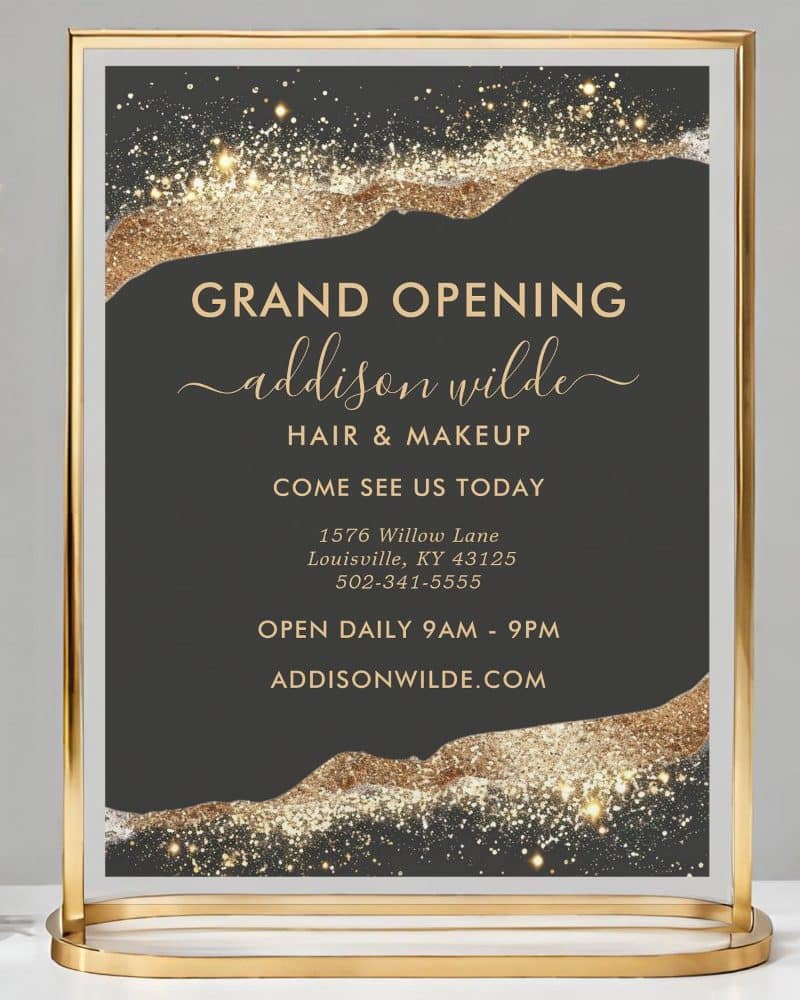 Gold framed sign announcing the grand opening of Addison Wilde Hair & Makeup, including address and hours.