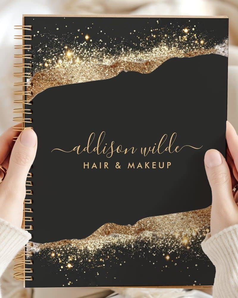 Black spiral notebook with gold glitter design and Addison Wilde Hair & Makeup in gold lettering.