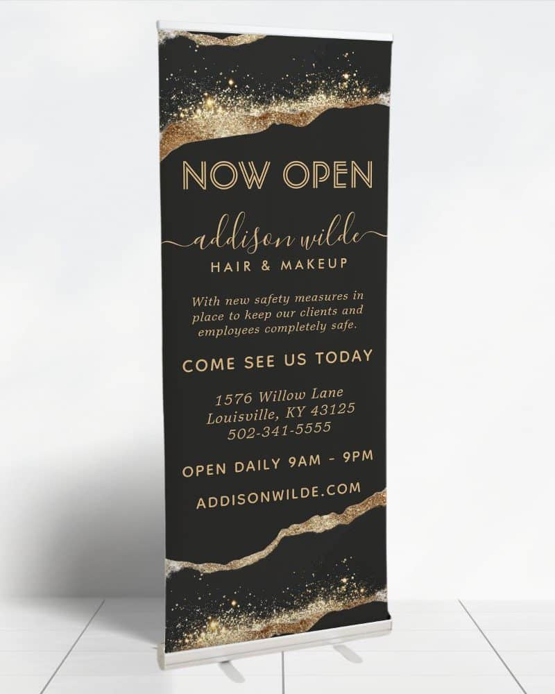 A black and gold "Now Open" banner for Addison Wilde Hair & Makeup, announcing their address and hours.
