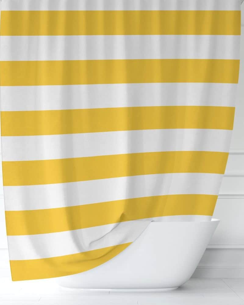 Yellow and white striped shower curtain partially draped over a white bathtub.