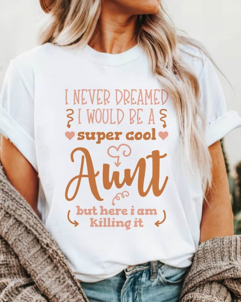 Woman wearing a white t-shirt that says, "I never dreamed I would be a super cool aunt, but here I am killing it."