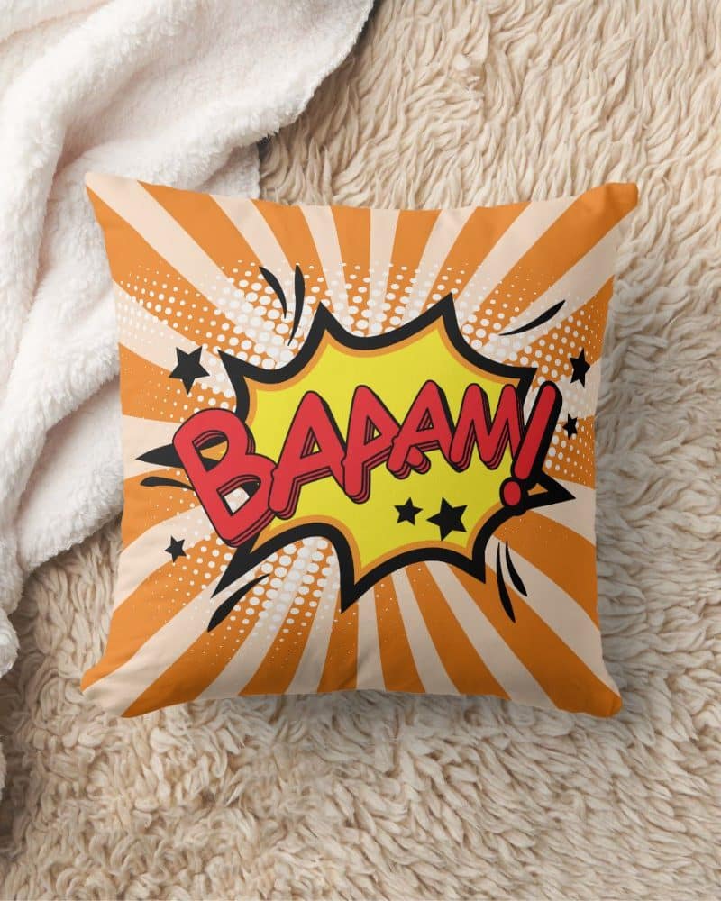 Orange throw pillow with a comic book style "BAAAAM!" graphic.