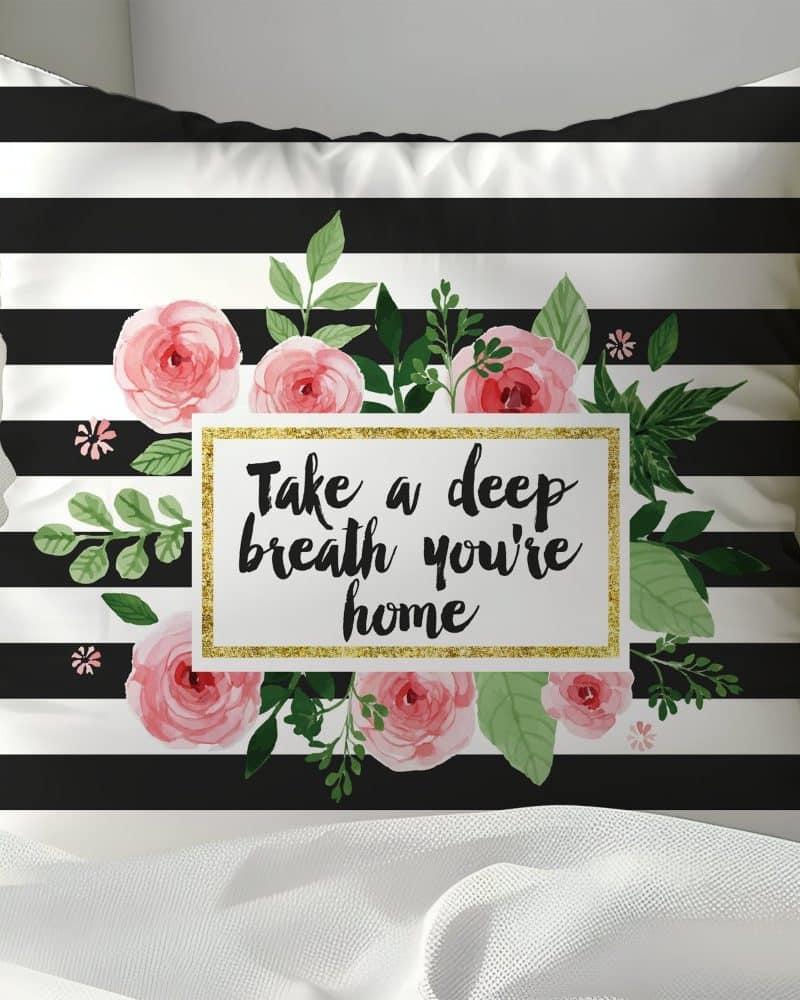 Black and white striped pillow with pink roses and the text Take a deep breath you're home.