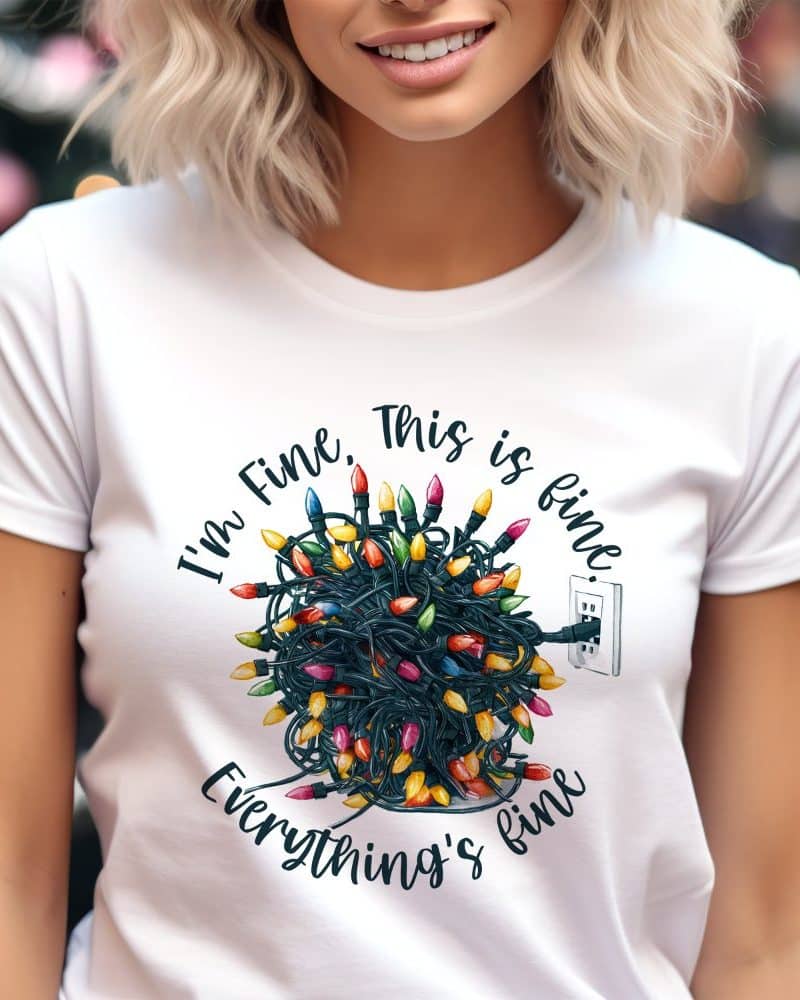 Woman wearing a white t-shirt featuring a design of tangled Christmas lights plugged into an outlet, with the text Im Fine, This is fine, Everythings fine.