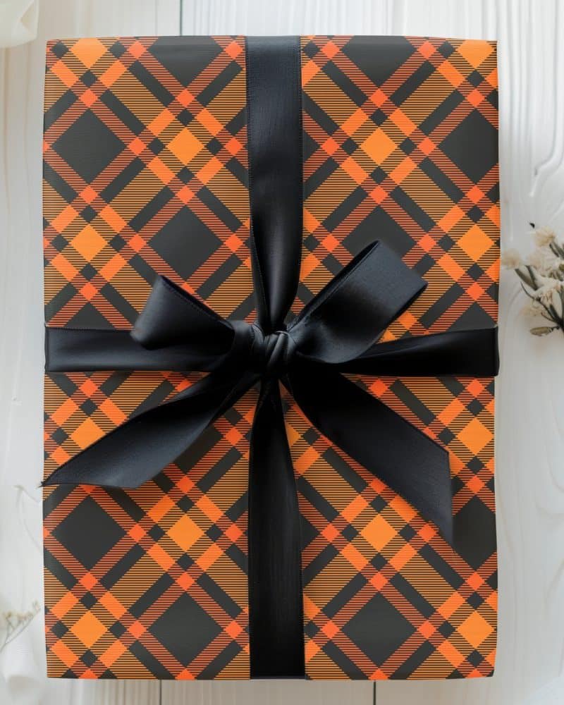 A gift wrapped in black and orange plaid paper with a black ribbon.
