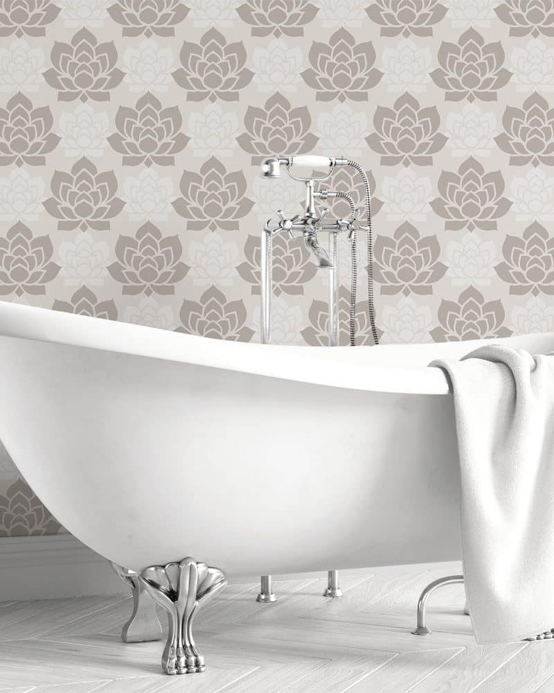 White clawfoot bathtub in front of a taupe floral wallpaper.
