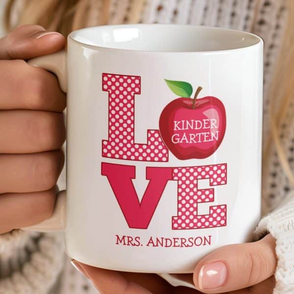 White Coffee Mug With Pink Polka Dot Love Graphic, A Red Apple With Kindergarten Text, And Mrs. Anderson'S Name.