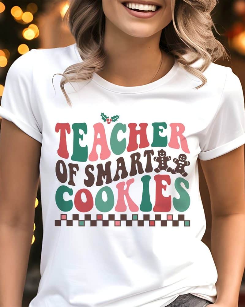Closeup of a woman wearing a white t-shirt that says Teacher of Smart Cookies in colorful retro lettering with gingerbread men.