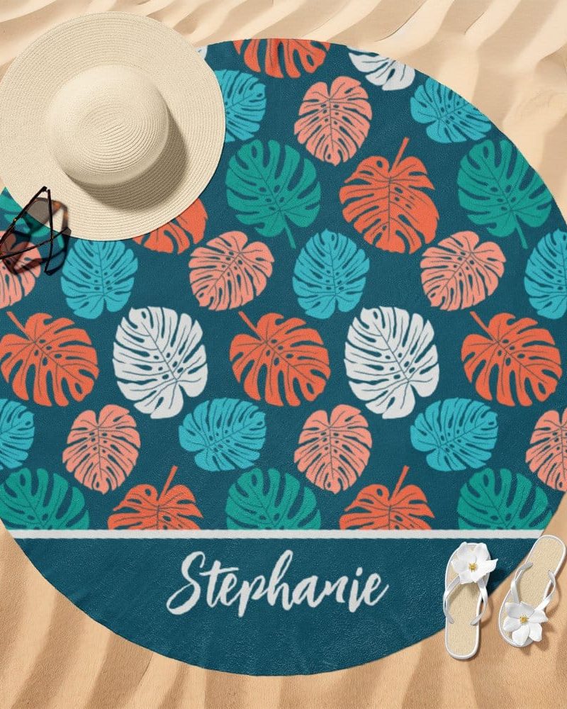 Round beach towel with a teal background and a repeating pattern of colorful monstera leaves. The name Stephanie is printed at the bottom.