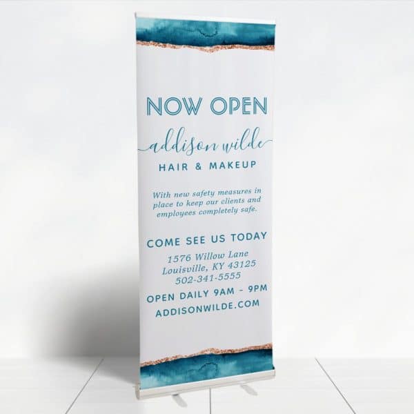 A Retractable Banner Announcing The Grand Opening Of Addison Wilde Hair &Amp; Makeup Salon. The Banner Includes The Salon'S Address, Phone Number, And Website.