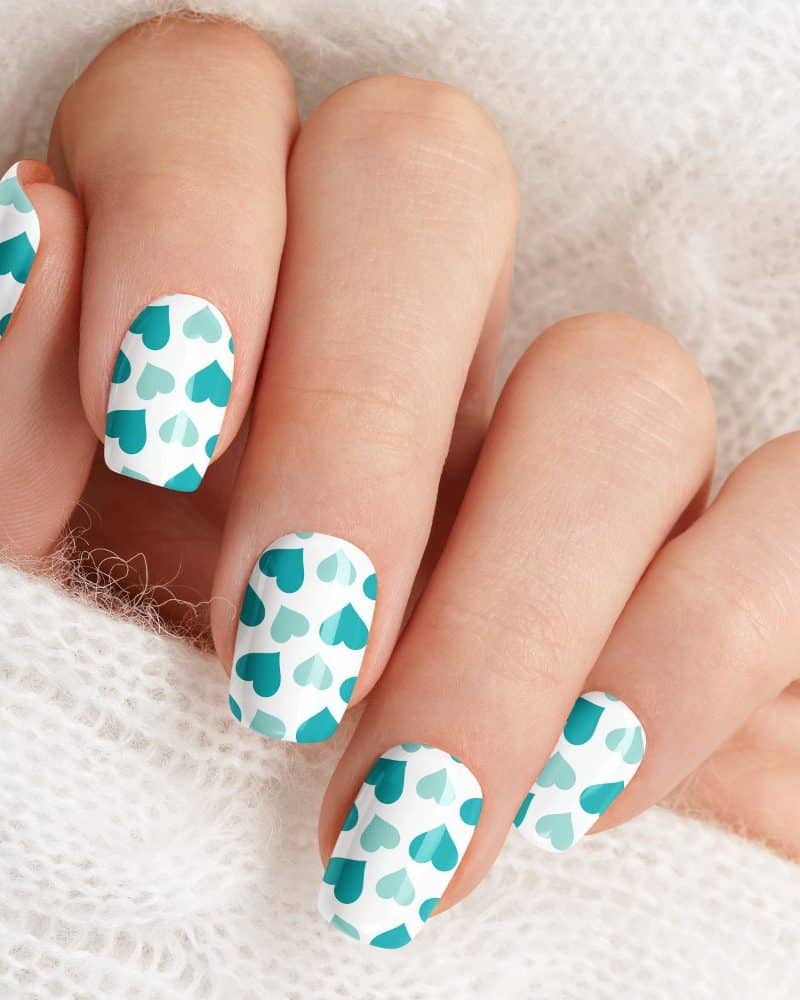 Close-up of a hand with fingernails painted with a teal heart pattern.