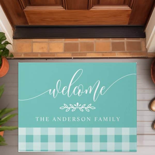 Teal Welcome Mat With White Script Lettering That Says Welcome And The Anderson Family, And A Bottom Border Of Teal And White Gingham.