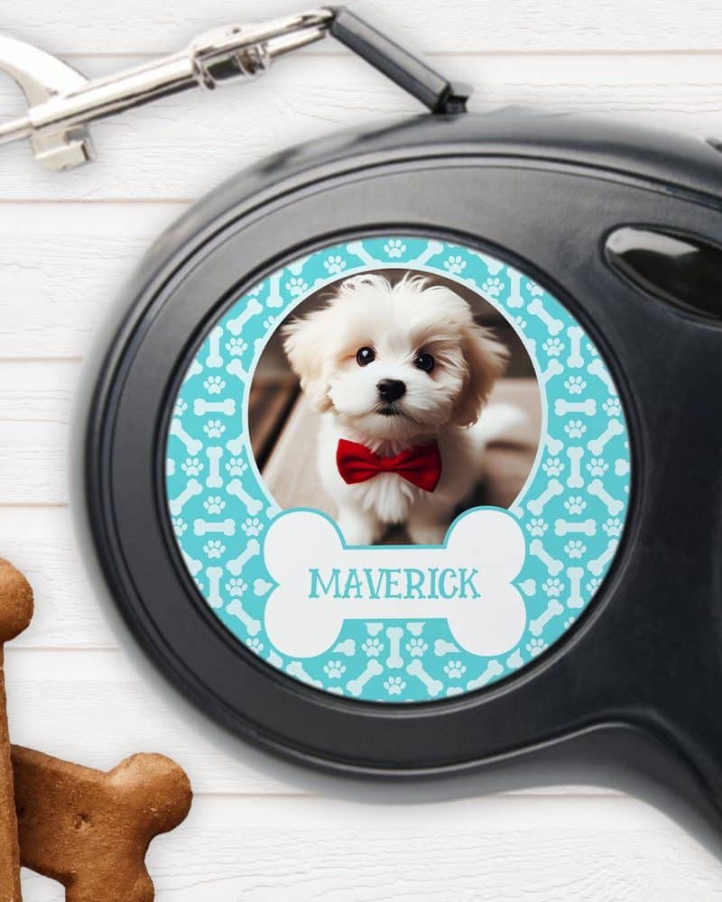 Retractable dog leash with a personalized photo of a small white dog wearing a red bow tie. The dogs name, Maverick, is printed on the leash.