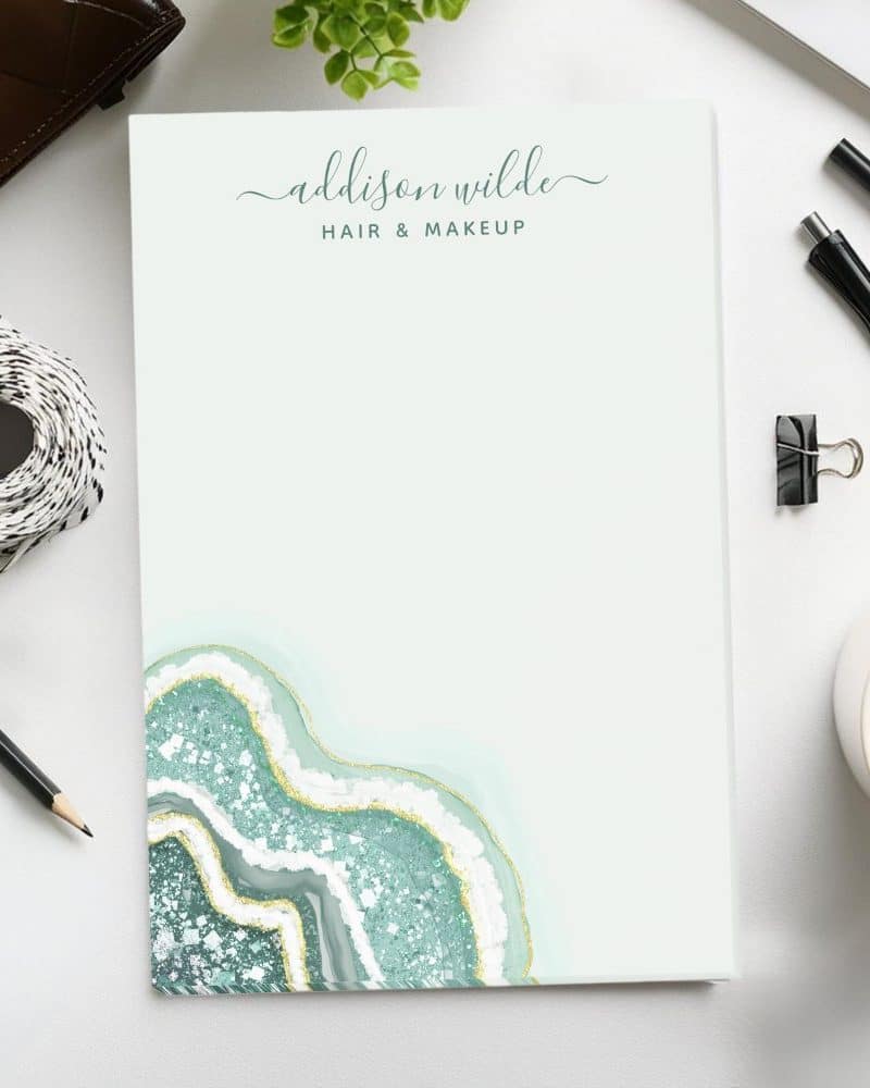 A notepad featuring a teal and gold agate design and the text Addison Wilde Hair & Makeup.