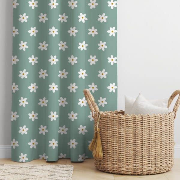 A Teal Curtain With A White Daisy Pattern Next To A Wicker Basket Holding White Pillows.