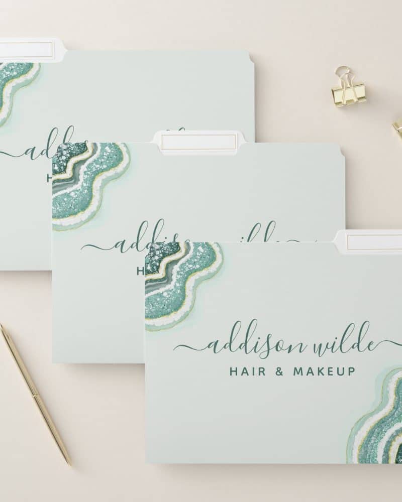 Three light teal file folders with a teal and gold agate design and the name Addison Wilde Hair & Makeup.