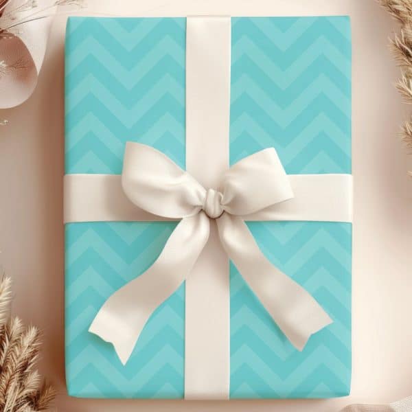 A Light Teal Gift Box With A Chevron Pattern, Topped With A Large Off-White Bow.