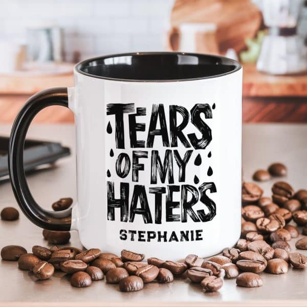 A Black And White Coffee Mug With The Text Tears Of My Haters And The Name Stephanie. Coffee Beans Are Scattered Around The Mug.