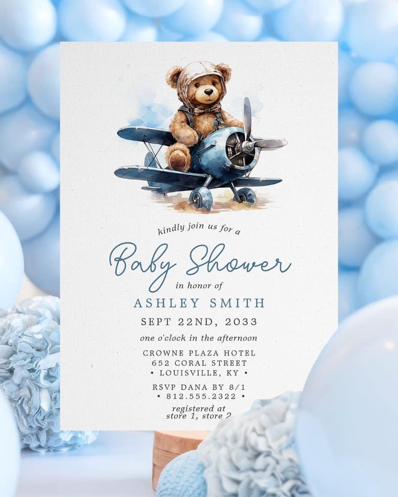 Baby shower invitation featuring a teddy bear in a blue airplane.