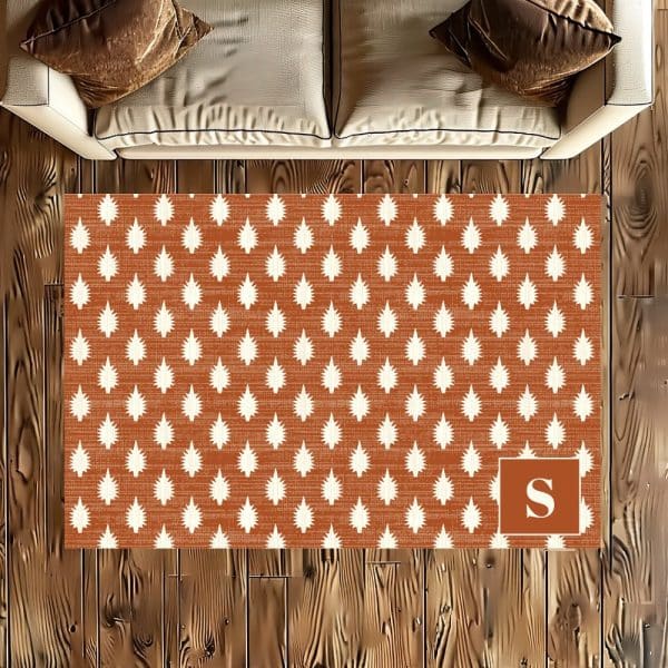 Russet Area Rug With A Repeating White Leaf Pattern And A Monogrammed Letter S In The Bottom Right Corner.