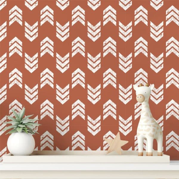 A Terracotta-Colored Wall With A Repeating Pattern Of White Distressed Chevron Arrows, Featuring A Small Giraffe Toy And A Succulent Plant On A Shelf In Front.