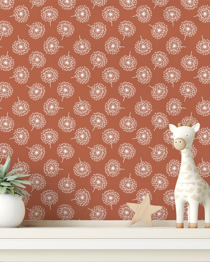A terracotta wall with a repeating pattern of white dandelions, featuring a small giraffe toy and a succulent plant on a white shelf.