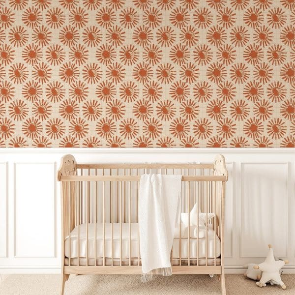 Light Wood Crib In Front Of A Wall Covered In A Repeating Terracotta Sun Pattern Wallpaper.